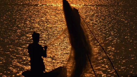 Fisherman sorting through his nets during sunset