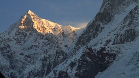 Golden sunlight illuminates the snow-capped mountain peaks of Himalayas